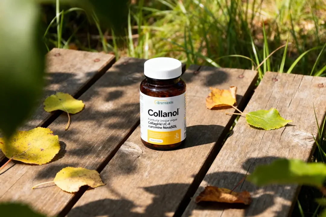 Bouteille de Collanol sur une table en bois entourée de feuilles d'automne jaunes